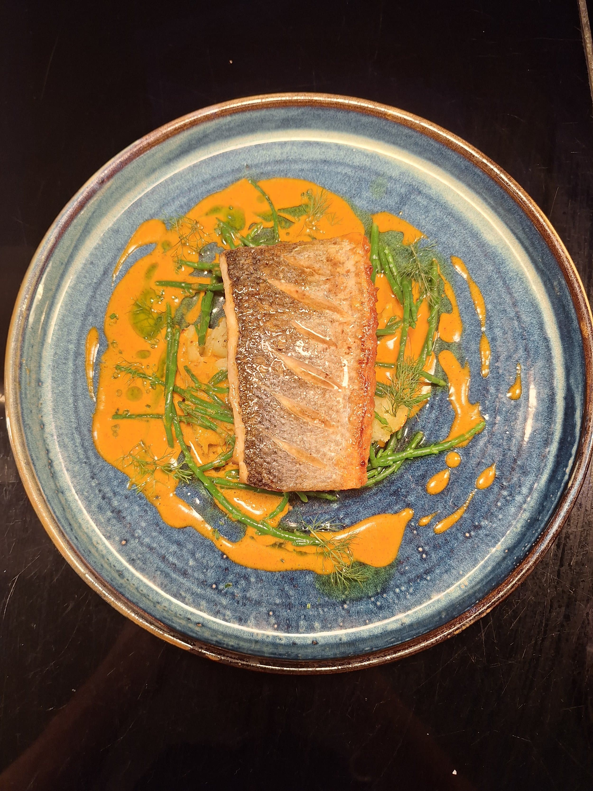 A fillet of fish with green beans, plated simply